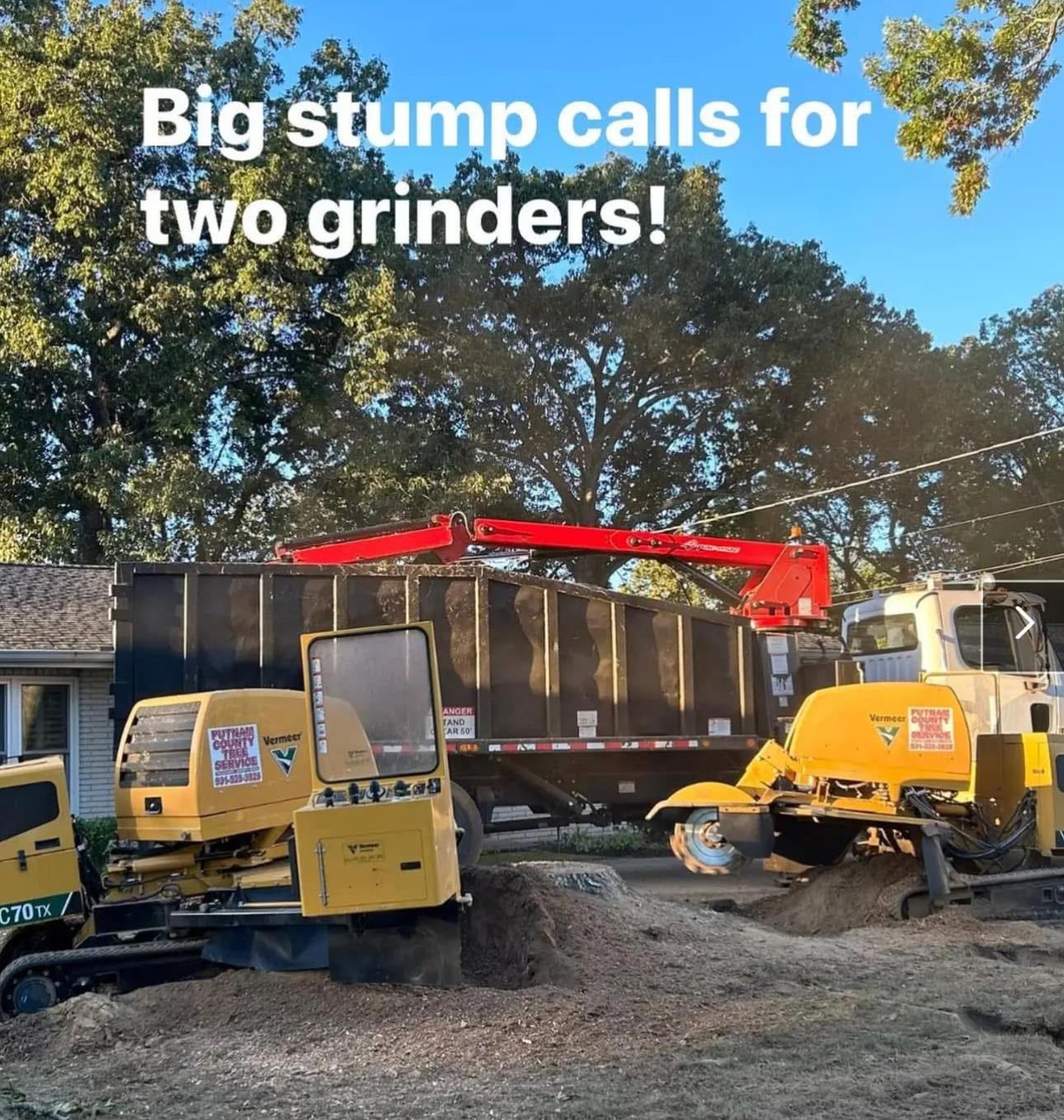 Two yellow stump grinders working to remove a tree stump. A large truck with a crane is in the background.