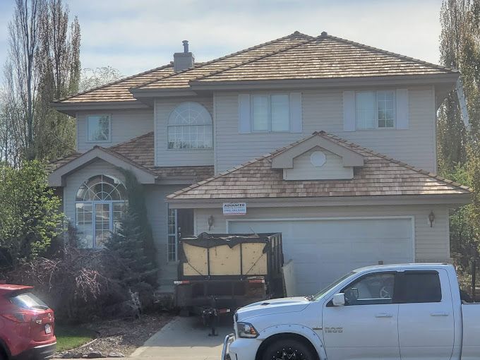 A white truck is parked in front of a large house.