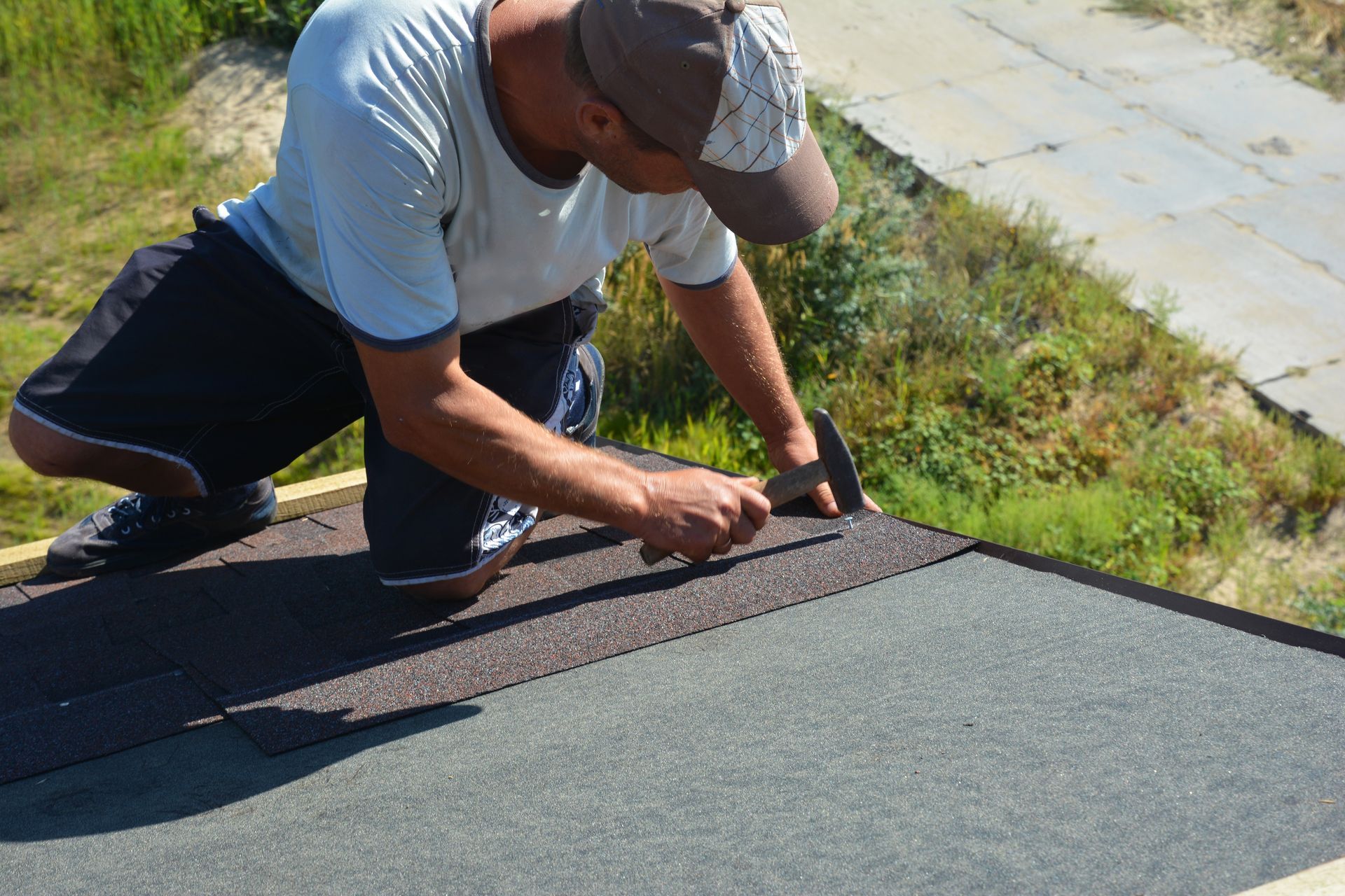 Worker installing shingles on a roof edge with a utility knife
