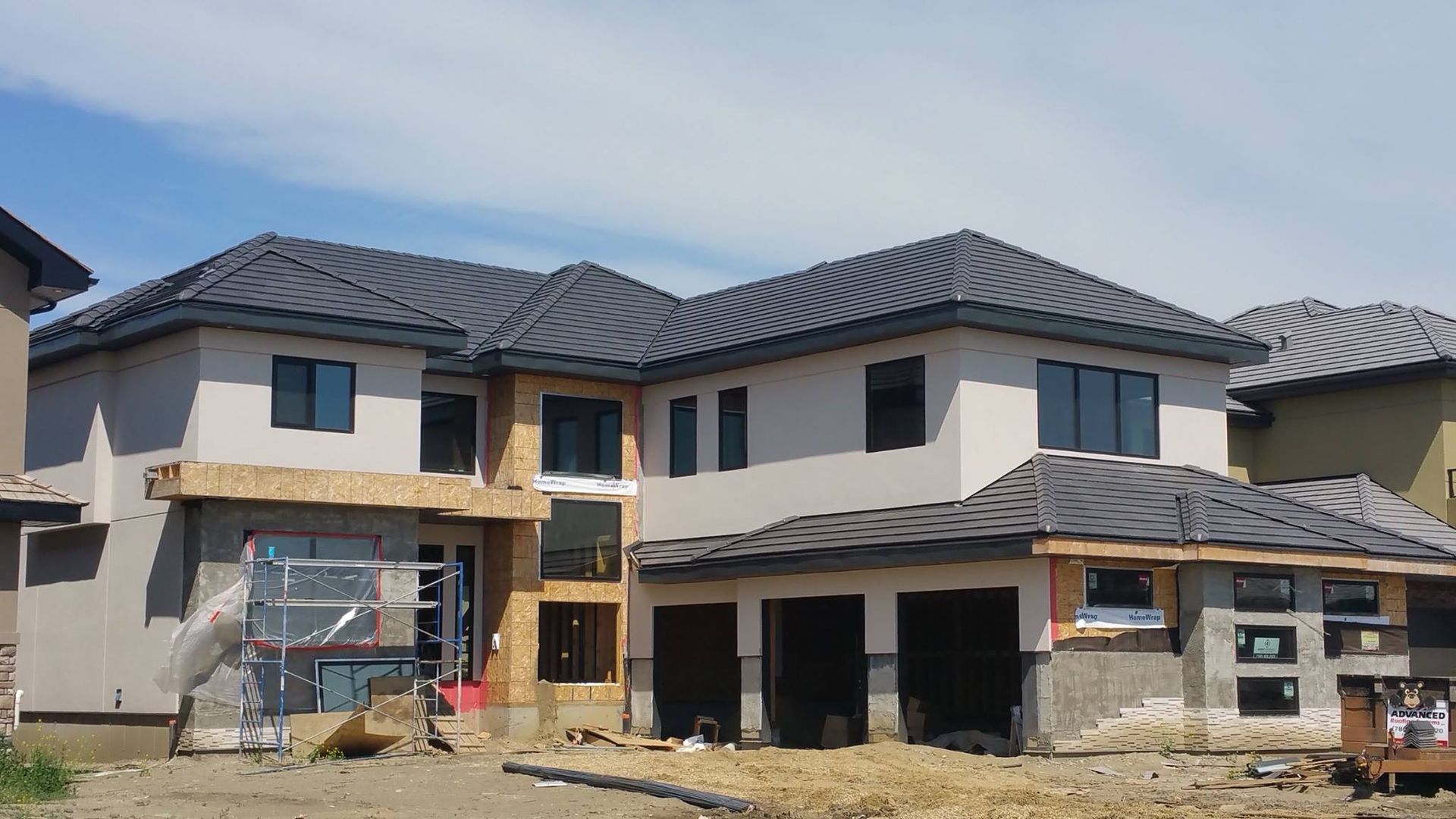 A large house is being built with a metal roof.