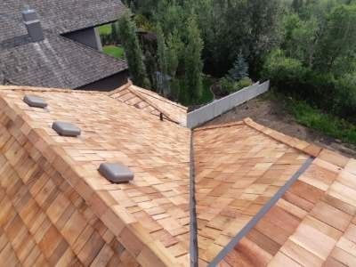An aerial view of a wooden roof with trees in the background.