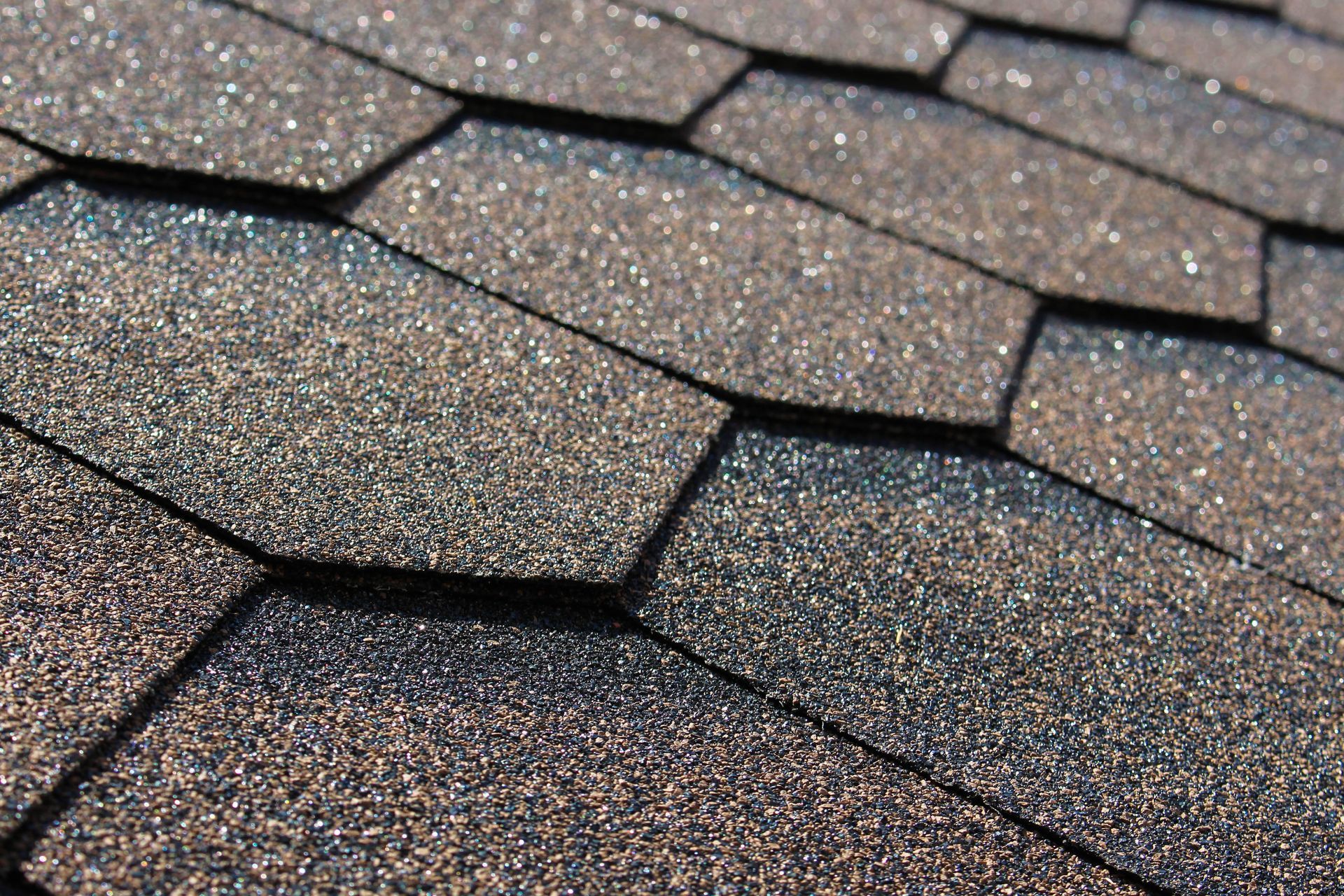 Dark gray asphalt roof shingles with a close-up textured pattern