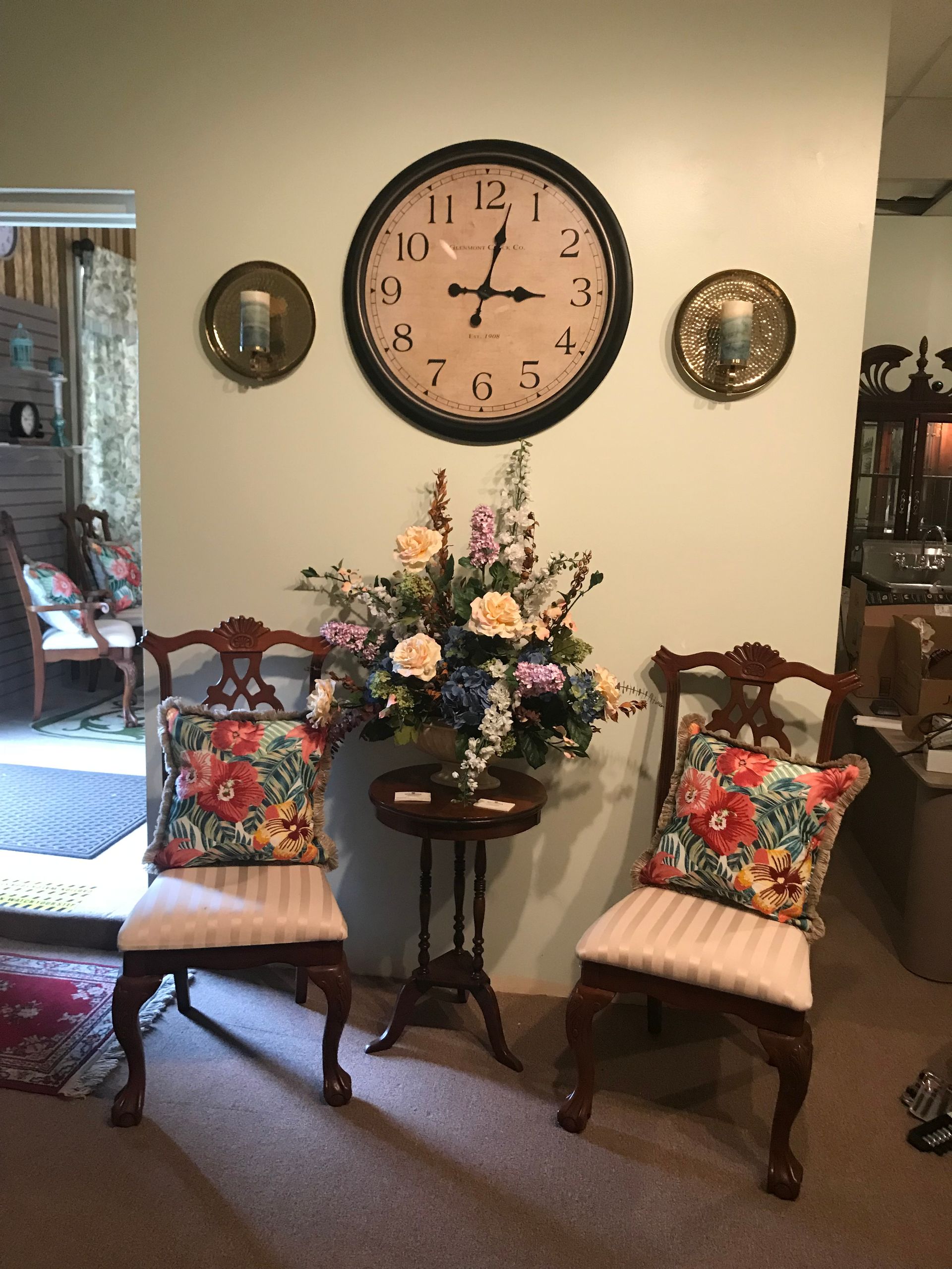 A living room with a clock on the wall and two chairs