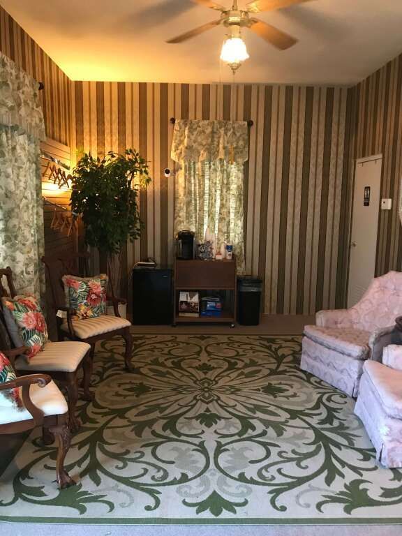 a living room with a rug , chairs , and a ceiling fan .