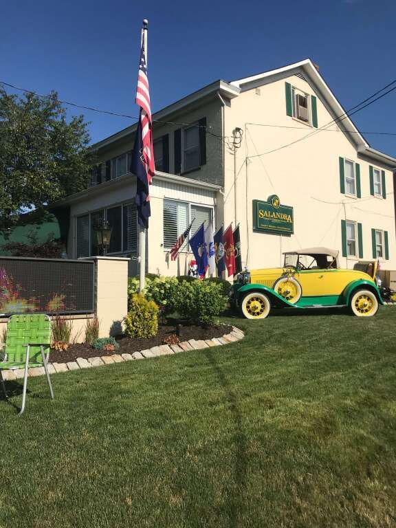 a yellow and green car is parked in front of a house .