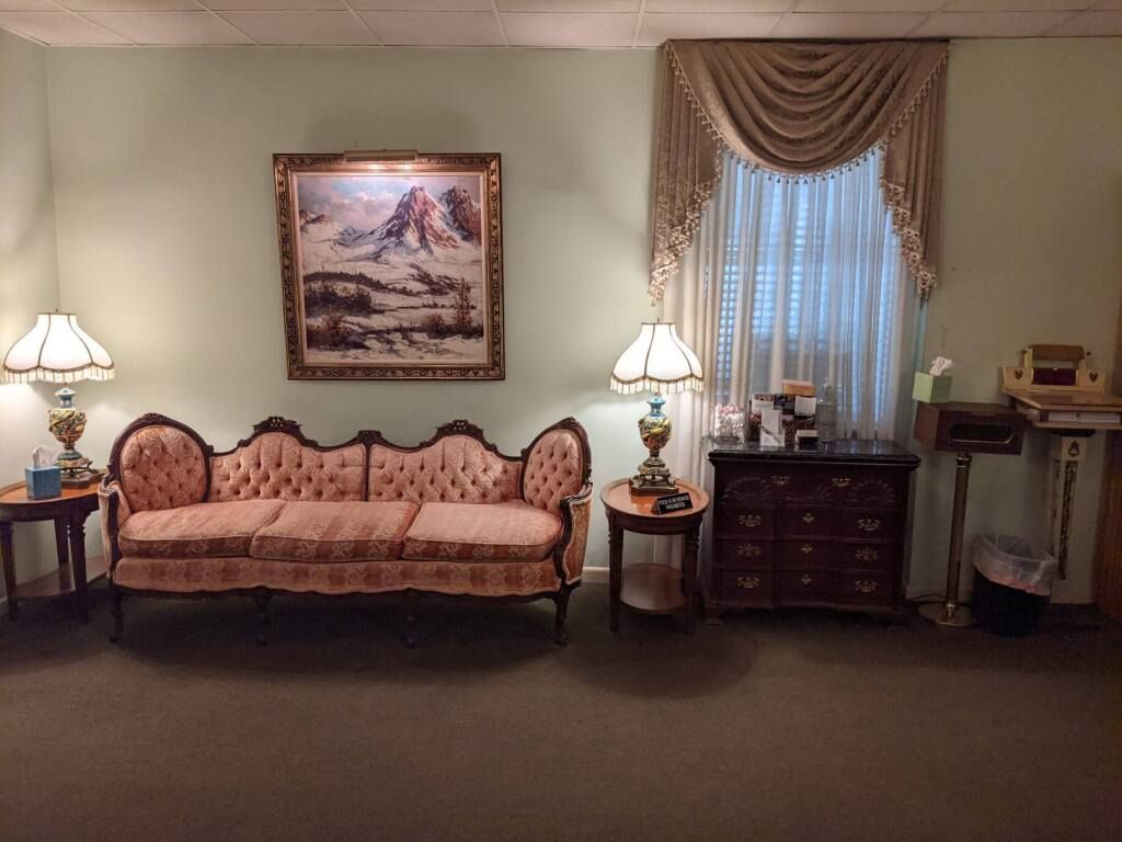 a living room with a couch , lamps , and a picture on the wall .