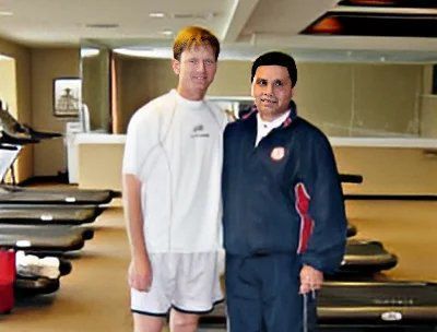Two men are posing for a picture in a gym