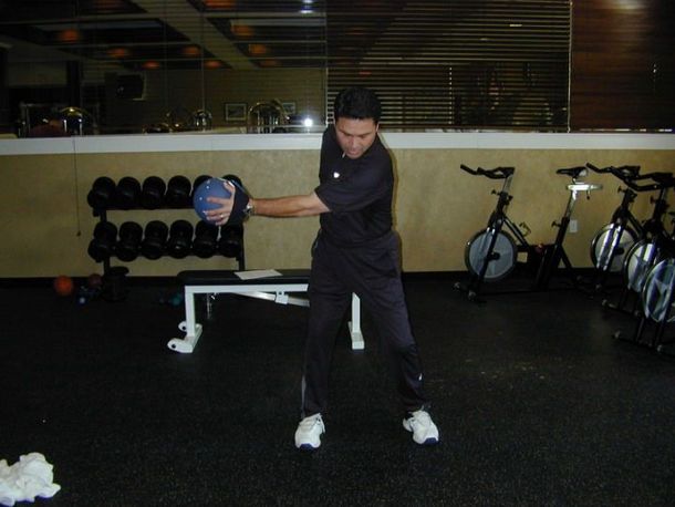 A man is holding a blue ball in a gym