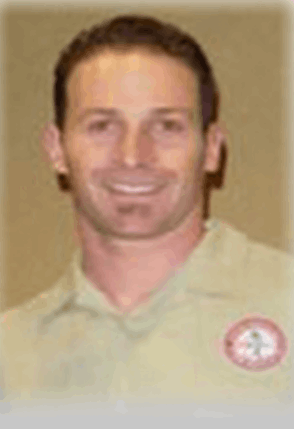 A man wearing a tan shirt with a badge on it