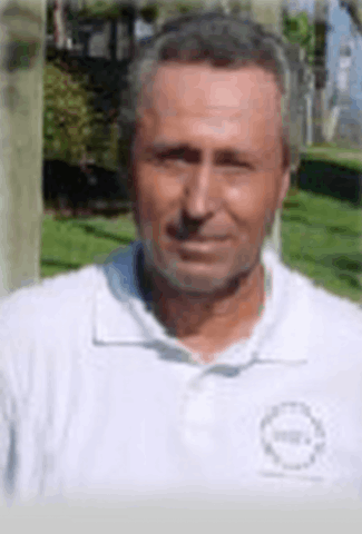 A man wearing a white polo shirt is smiling for the camera
