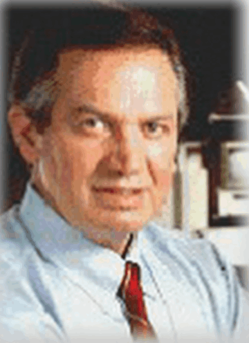A man in a blue shirt and red tie looks at the camera