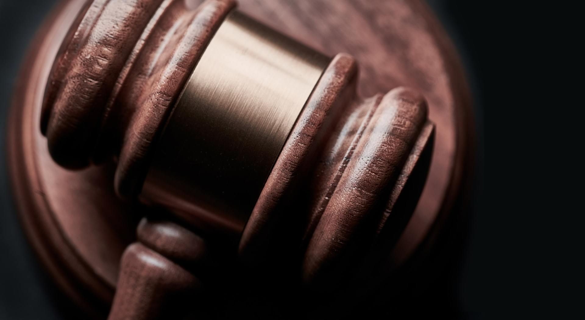 Wooden gavel on a dark surface, used in a courtroom for making official rulings.