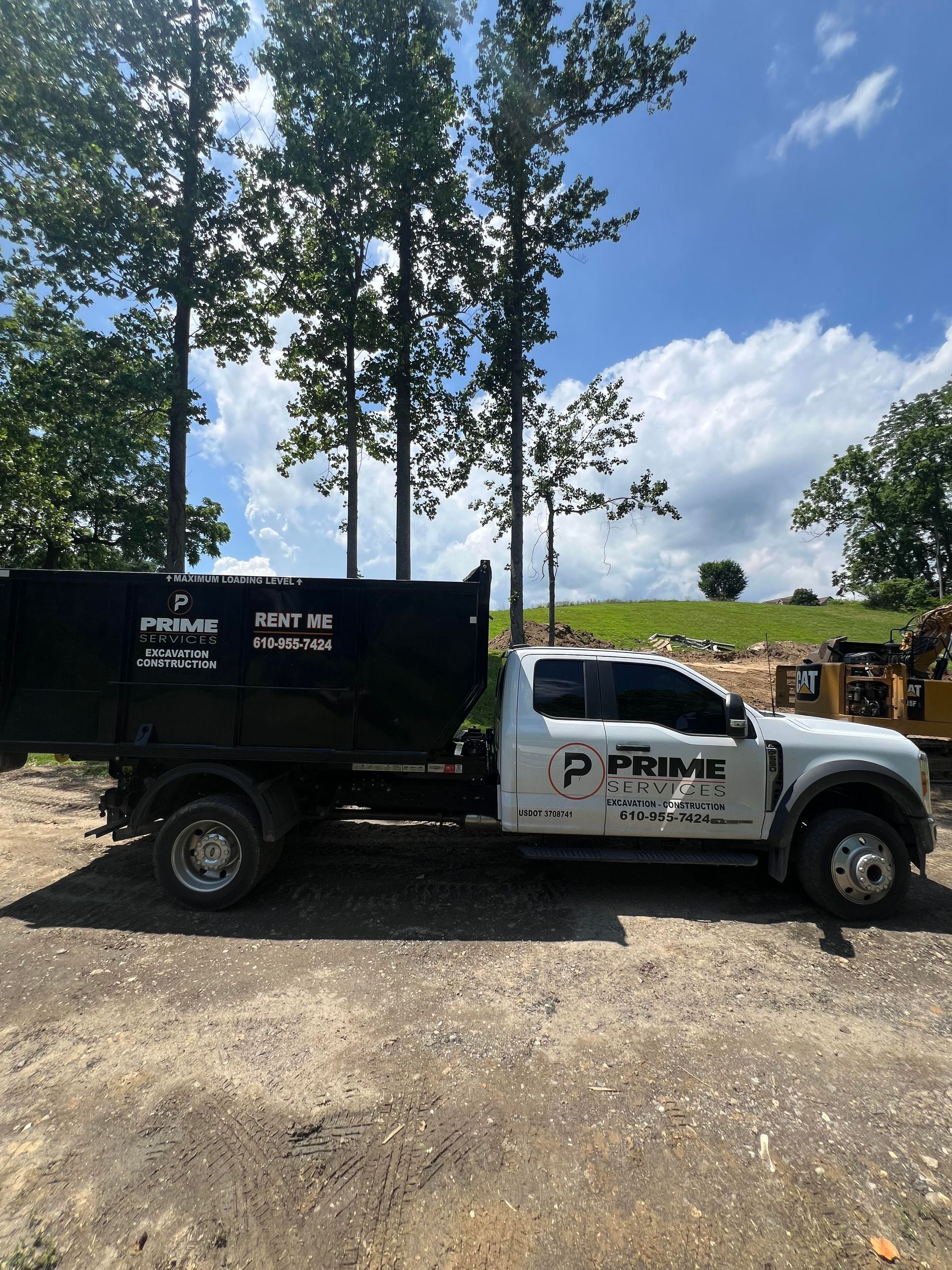 White and black utility truck with PRIVE logo parked on gravel near trees under a blue sky