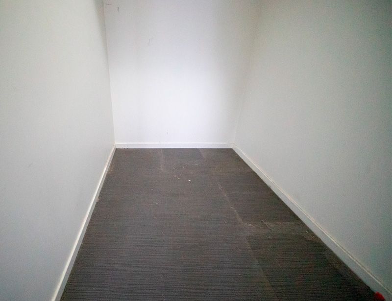 Narrow empty white hallway with dark carpeted floor