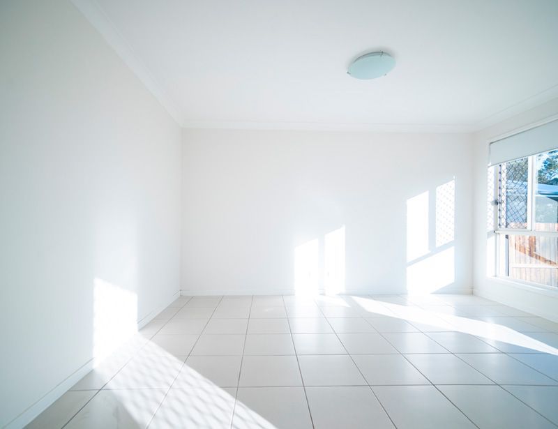 Bright empty white room with tiled floor and sunlight streaming through windows