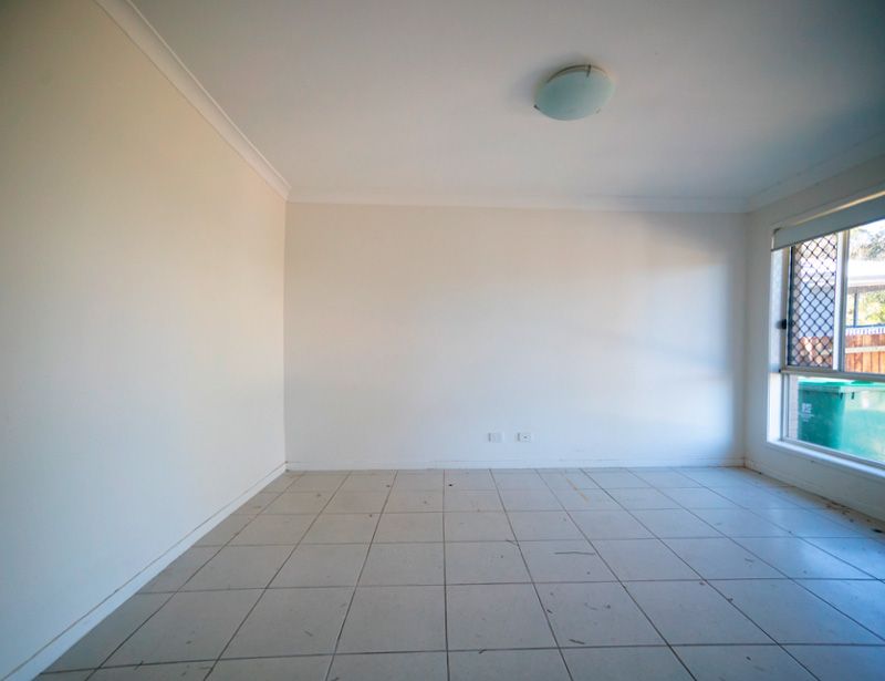 Empty tiled room with white walls, ceiling light, and large window on the right