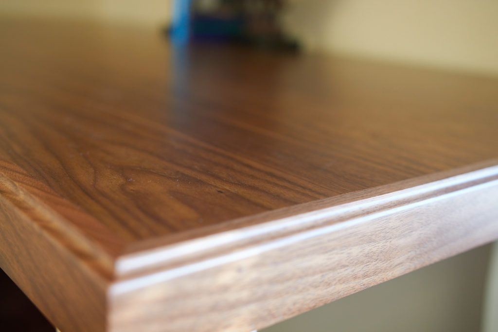 a close up of a wooden table with a lamp in the background .