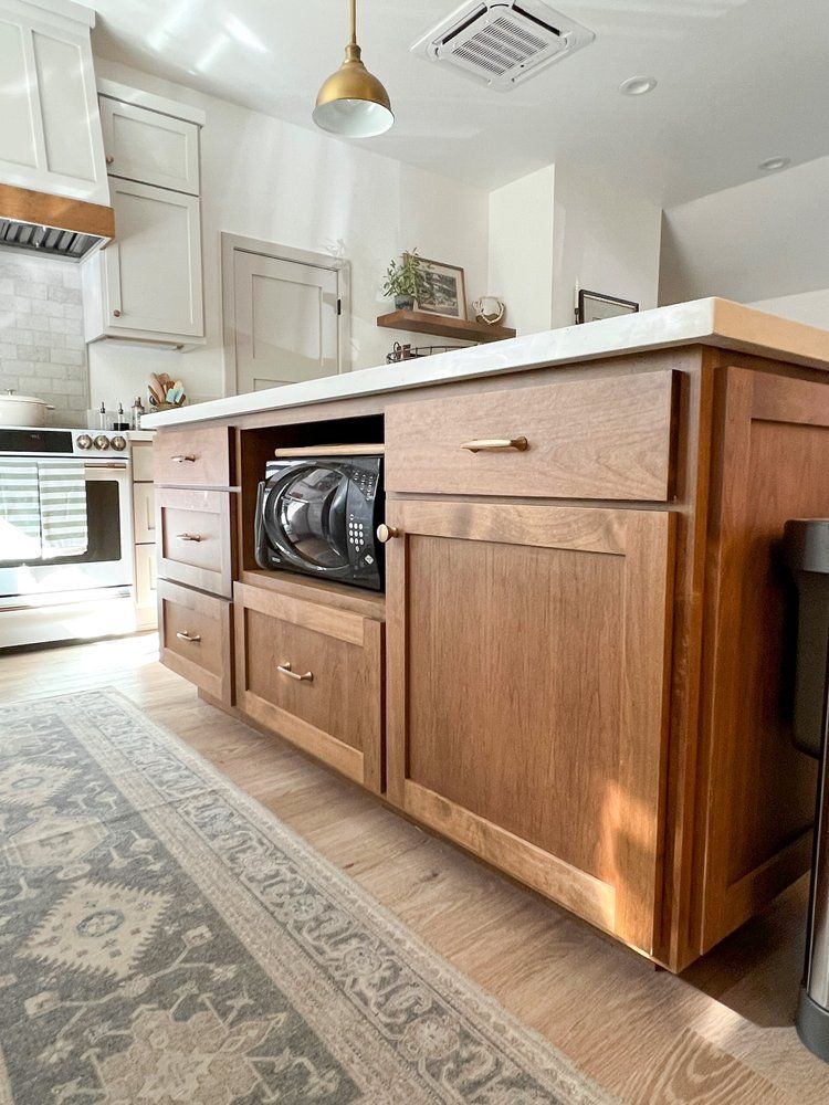 a kitchen with wooden cabinets and a microwave on the island .