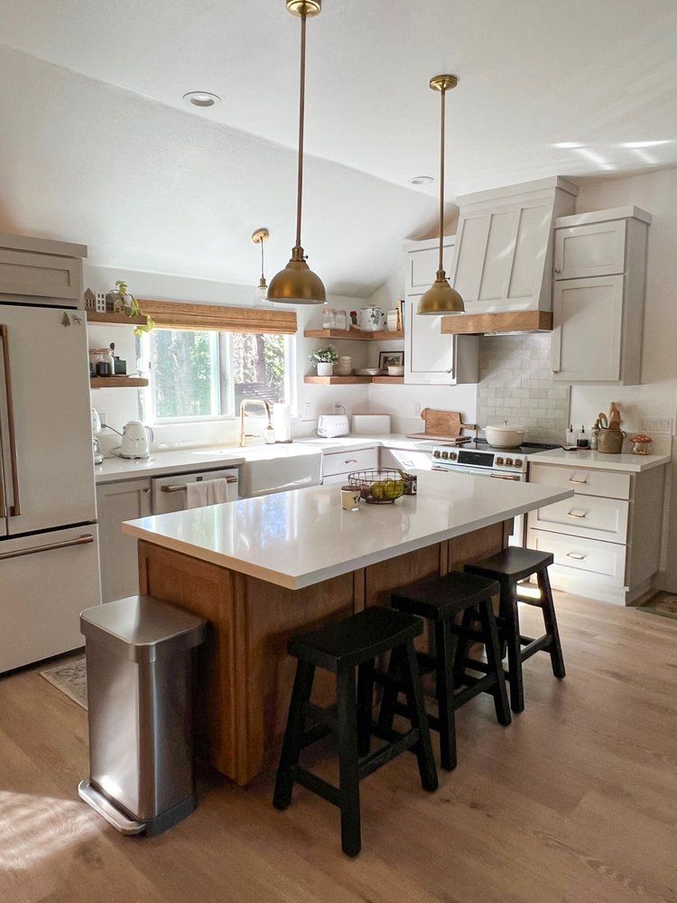 a kitchen with a large island , stools and a trash can .