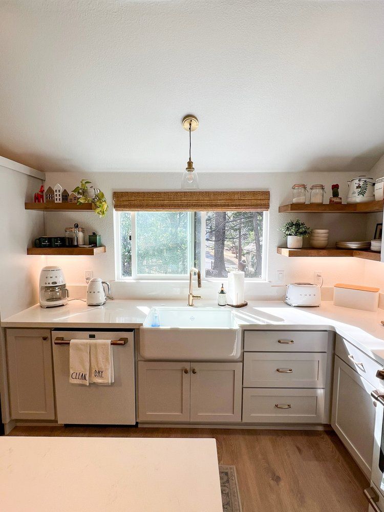 a kitchen with white cabinets , a sink , a dishwasher , and a window .