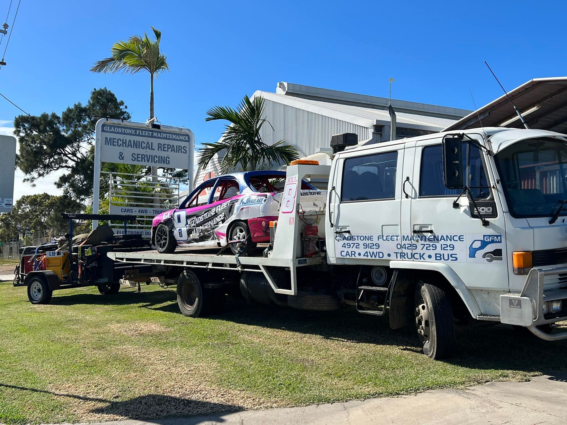 A White Tow Truck Carrying a Race Car and a Small Buggy on a Sunny Day — Gladstone Fleet Maintenance In Gladstone, QLD