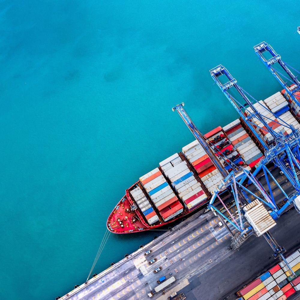 An aerial view of a large container ship docked in a harbor.