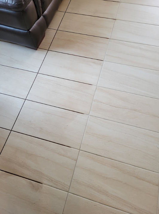 Beige tiled floor with a dark brown sofa corner in the upper left.