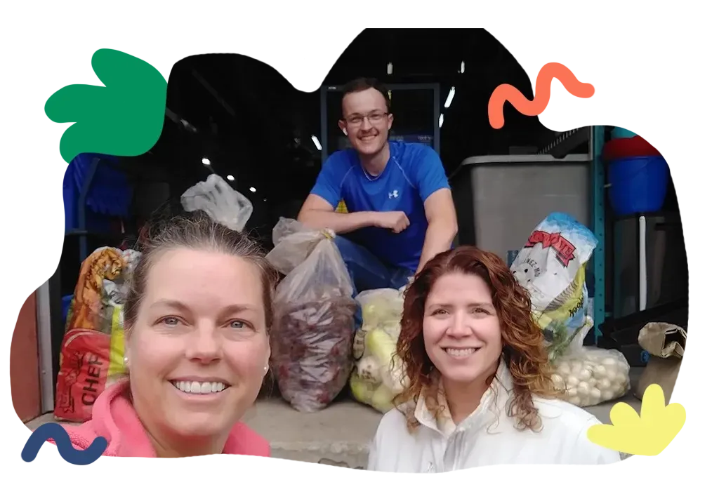 Three people posing in front of bags of produce at a market stand