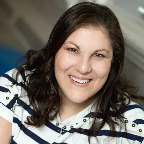 Smiling woman in a white striped hoodie against a blurred indoor background