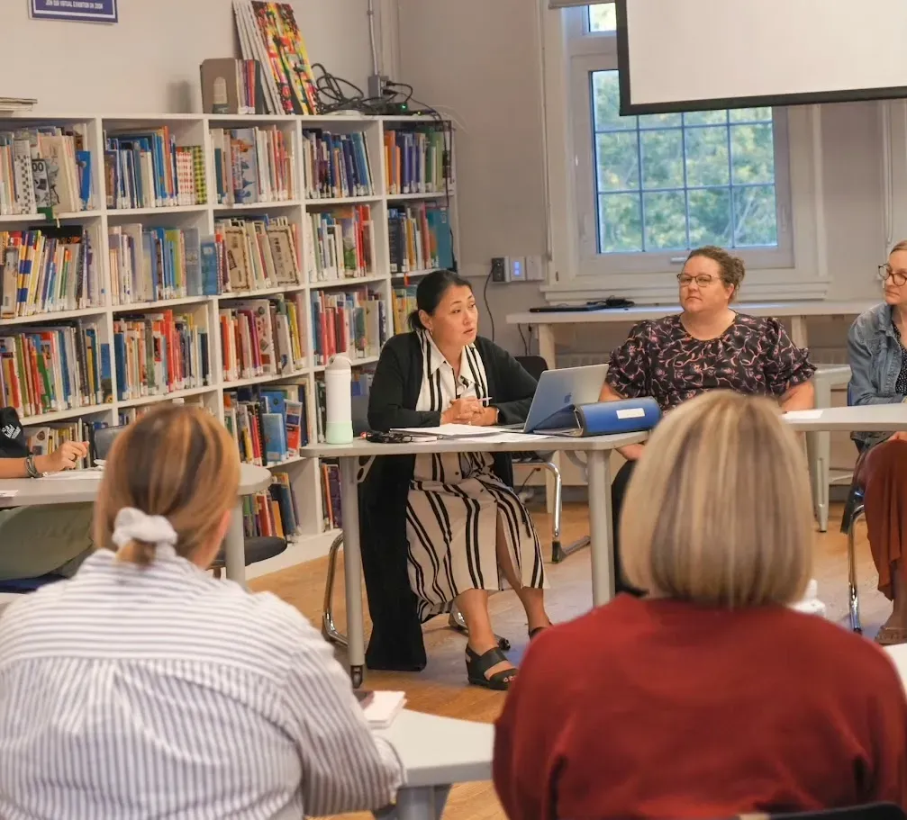 People seated in a library room listening to a panel discussion at a table