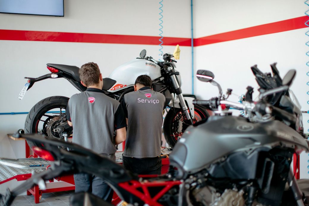 Uma motocicleta Ducati vermelha sendo revisada por um mecânico em uma oficina autorizada Ducati.
