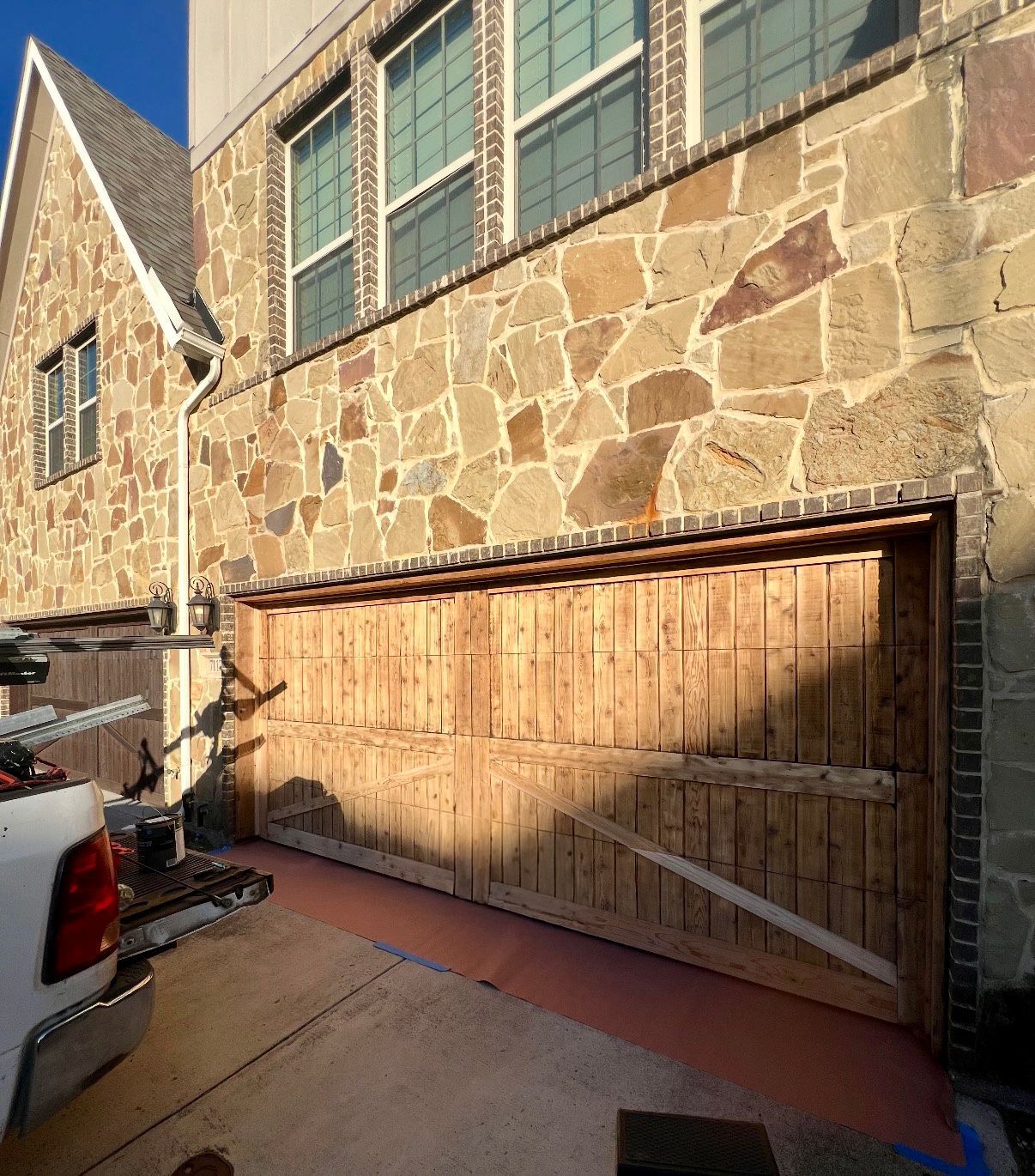 Stone garage exterior with large wooden door and parked truck in driveway