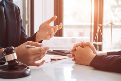 Businesspeople in a meeting, gesturing over documents at a sunlit desk