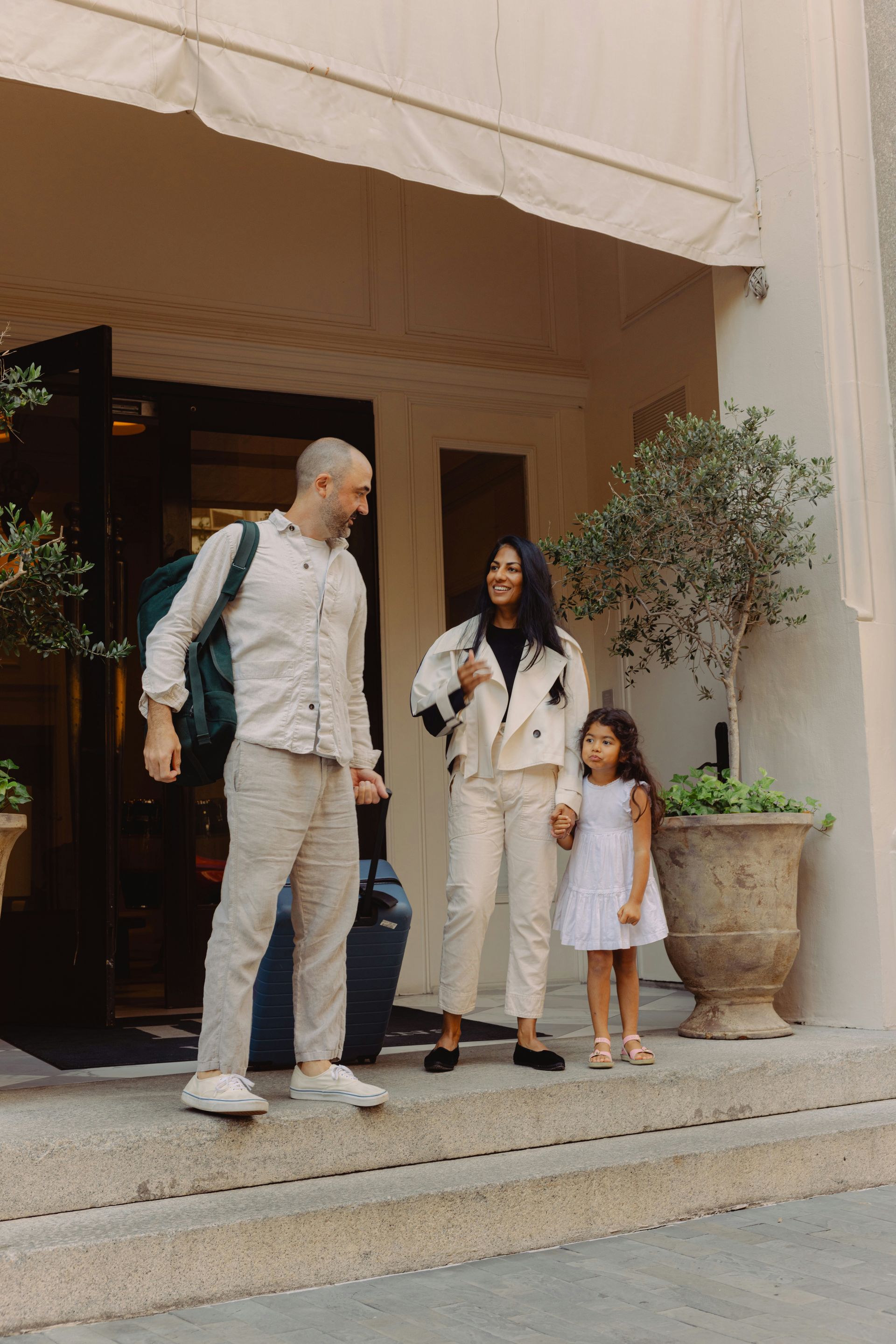 Family standing outside a doorway under a cream awning, with a small child beside them.