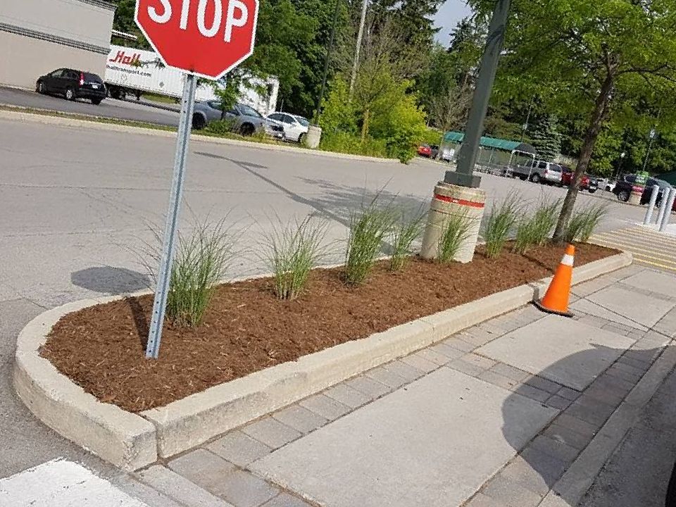 A stop sign is sitting on the side of the road next to a planter.