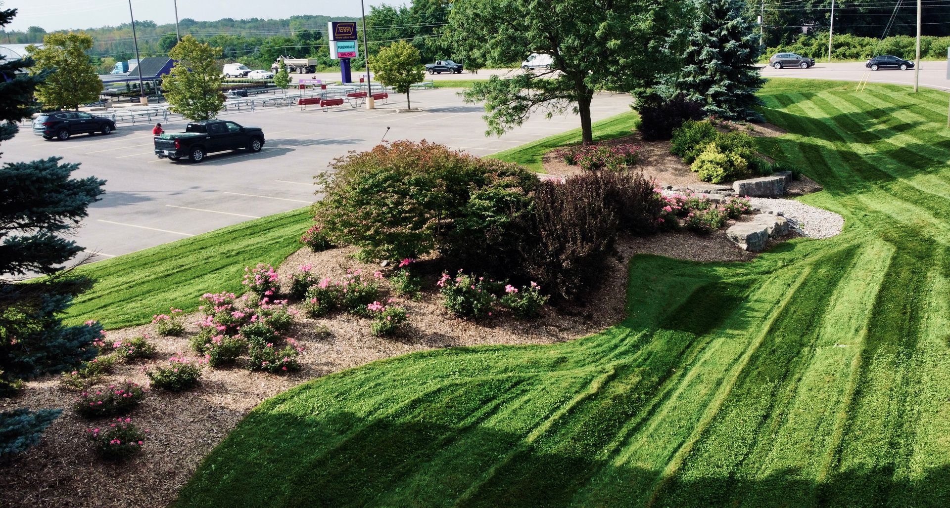 An aerial view of a lush green lawn with a parking lot in the background.