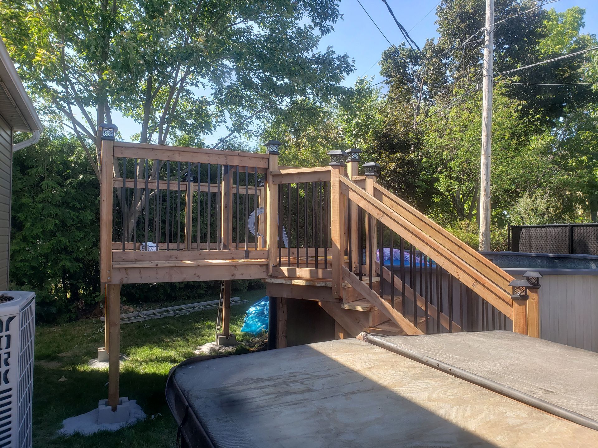 Une terrasse en bois avec des escaliers menant à un bain à remous