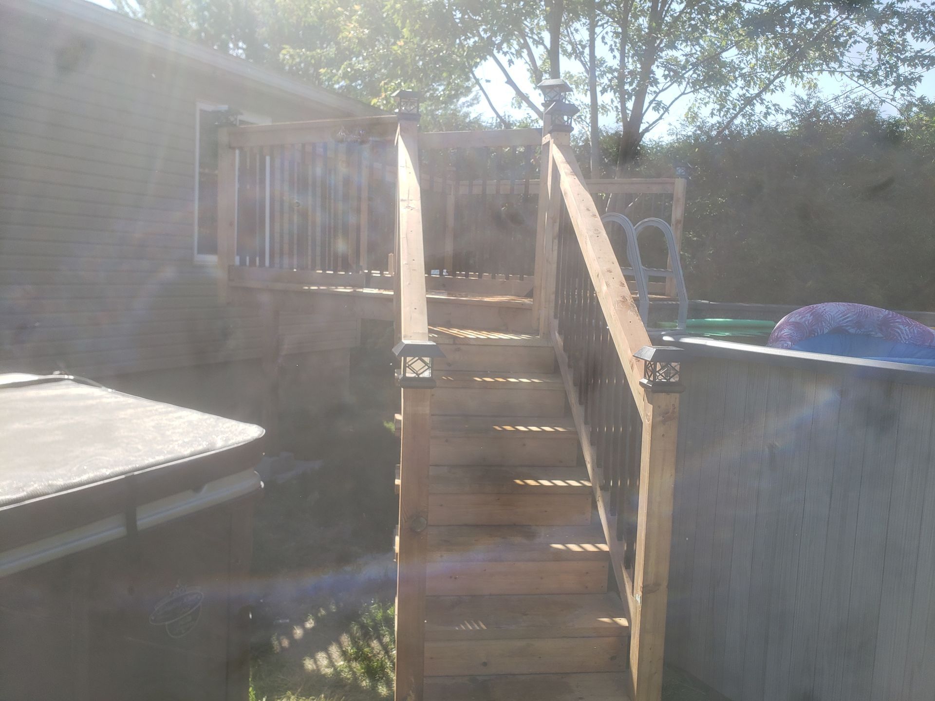Une terrasse en bois avec des escaliers menant à une piscine