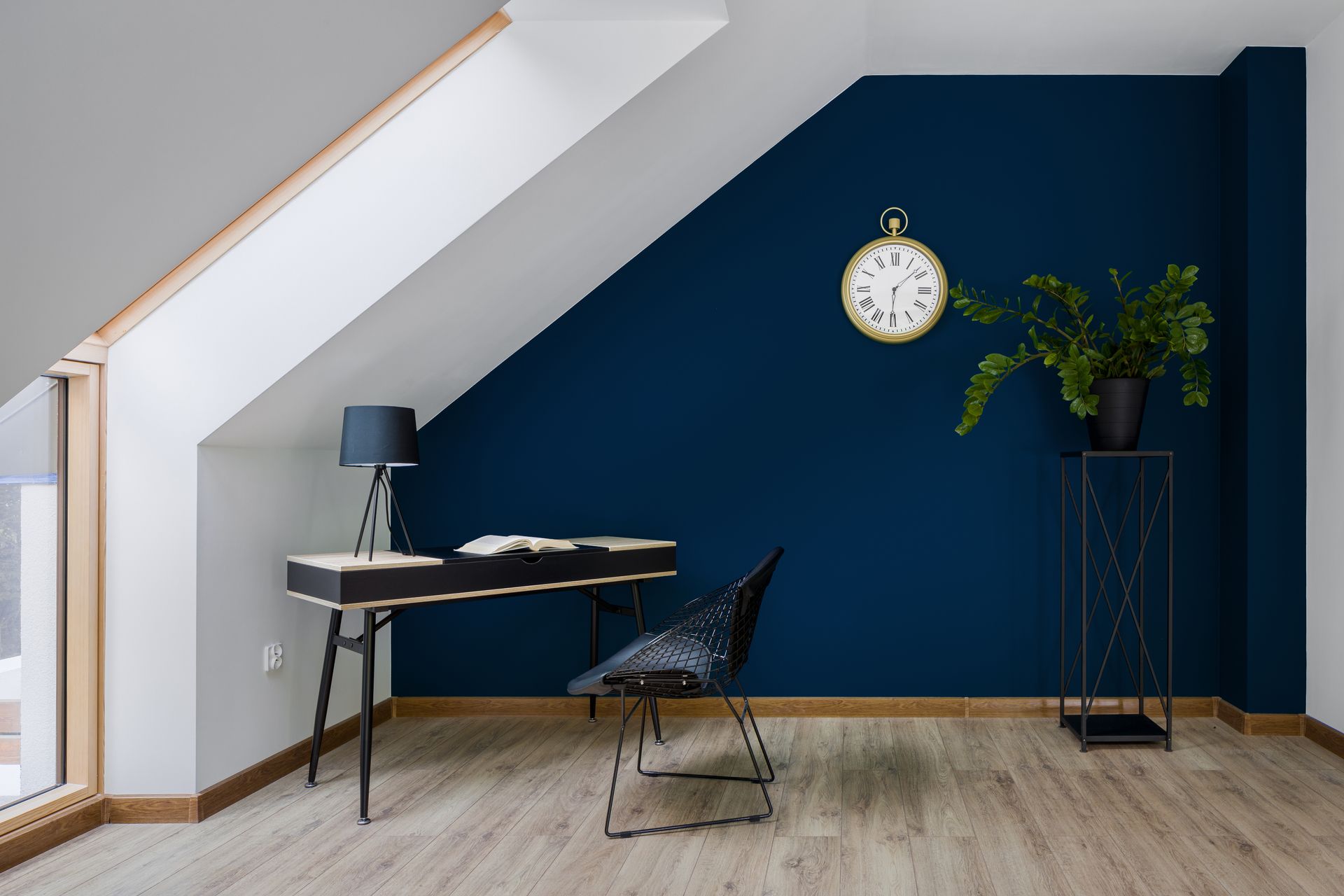 Une pièce avec un bureau, une chaise, une lampe et une horloge au mur.