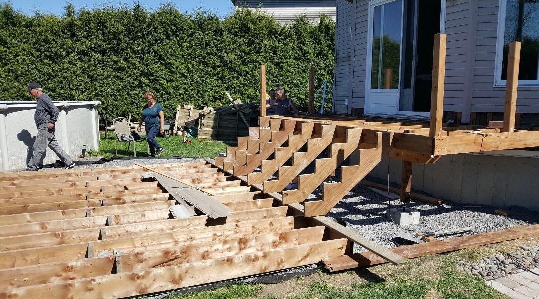 Une terrasse en bois est en cours de construction dans l'arrière-cour d'une maison.