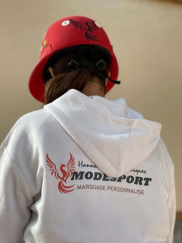 Personne vue de dos portant un casque rouge et un sweat-shirt blanc avec le logo « Handicap Mode Sport ».