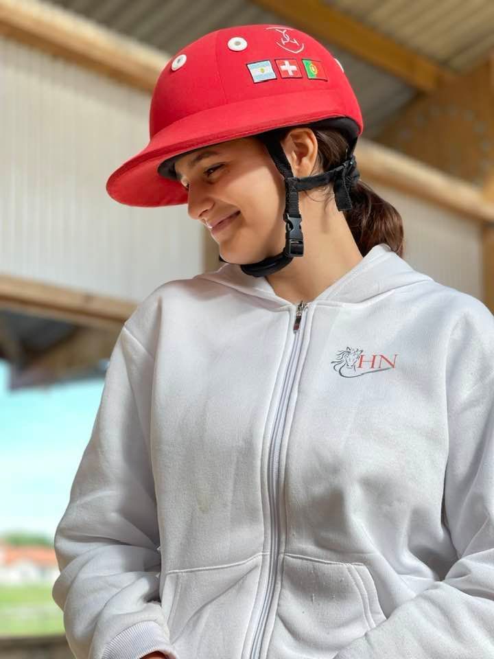 Une personne portant un casque rouge et une veste grise regarde vers le bas, à l'intérieur.