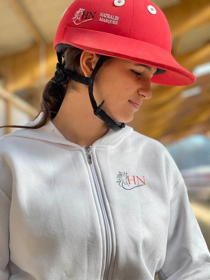 Une personne portant un casque rouge et une veste blanche regarde vers le bas à l'intérieur.