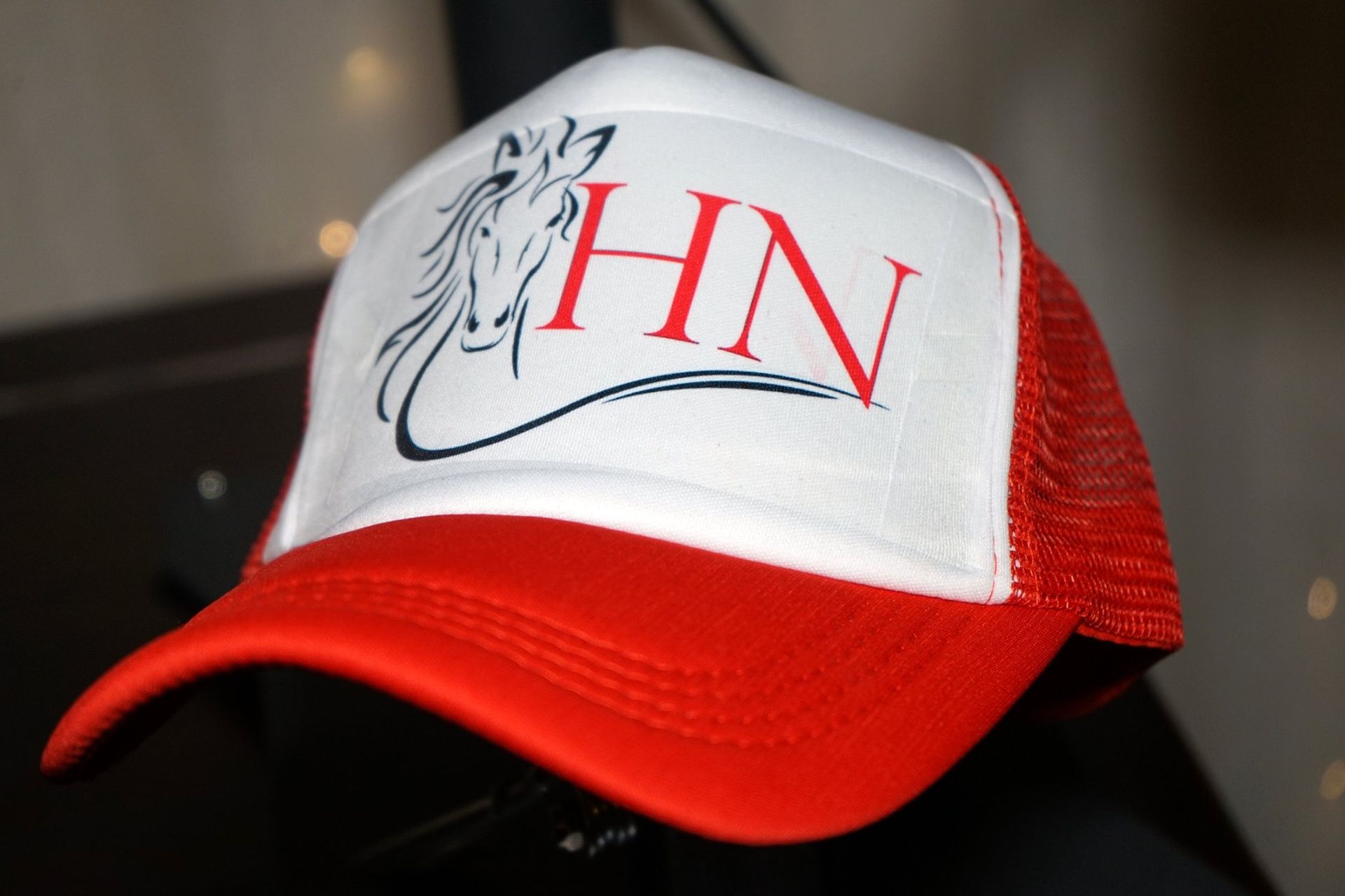Casquette trucker blanche et rouge avec un lion noir et le logo « HN » rouge sur le devant