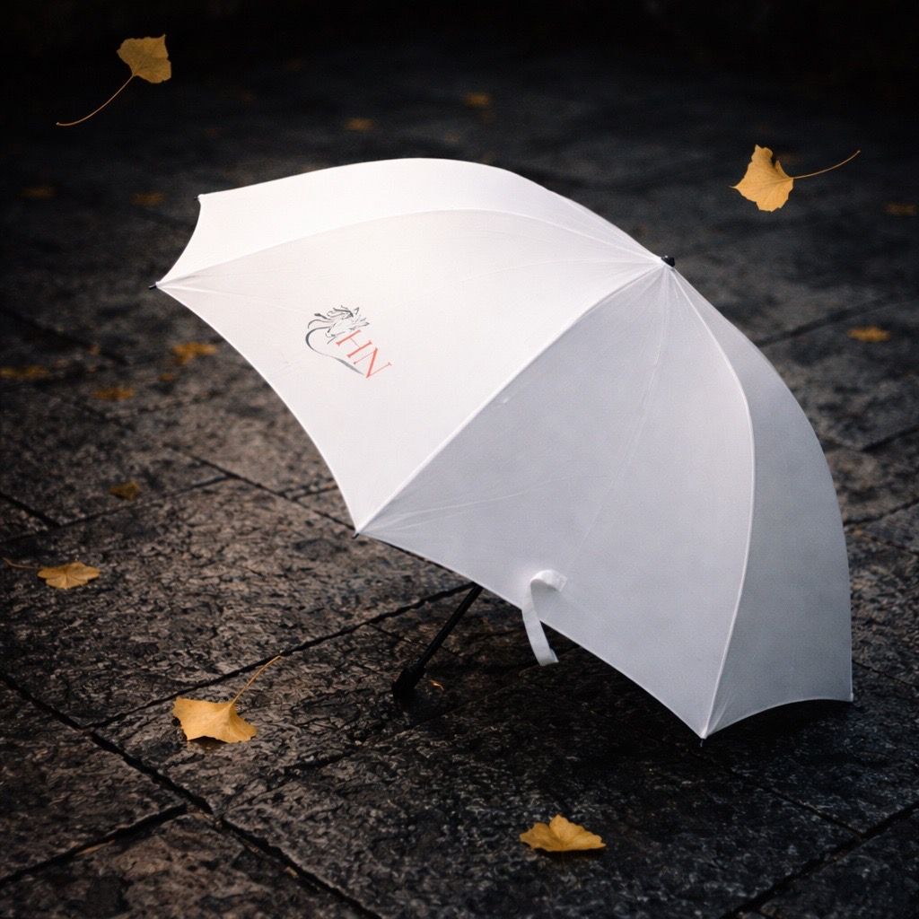 Parapluie blanc sur un trottoir sombre et humide parsemé de feuilles jaunes.