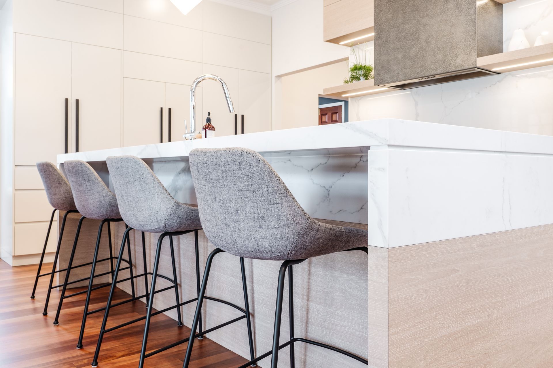 Modern Kitchen Island With Four Gray Bar Stools and a Chrome Faucet — PKJ Design in Unanderra, NSW