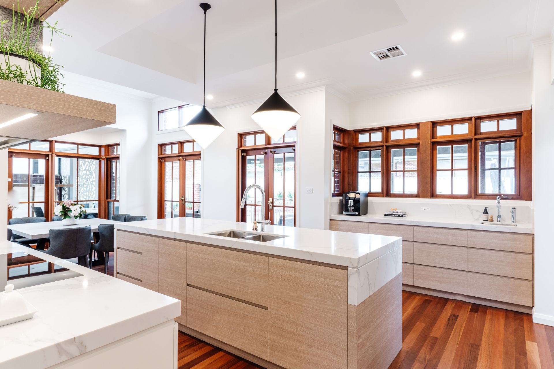 Kitchen With White Island, Wood Floors, Large Windows, and Pendant Lights — PKJ Design in Unanderra, NSW