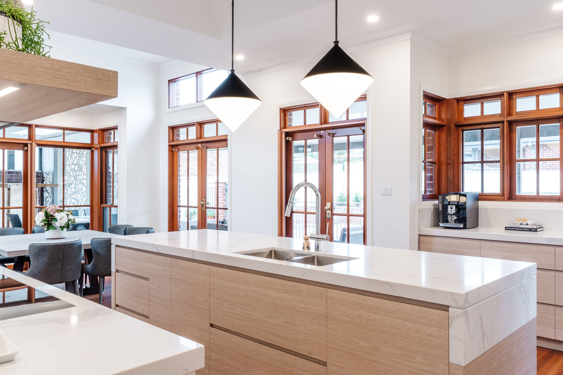 Kitchen With White Island, Pendant Lights, and Wood-framed Windows — PKJ Design in Unanderra, NSW