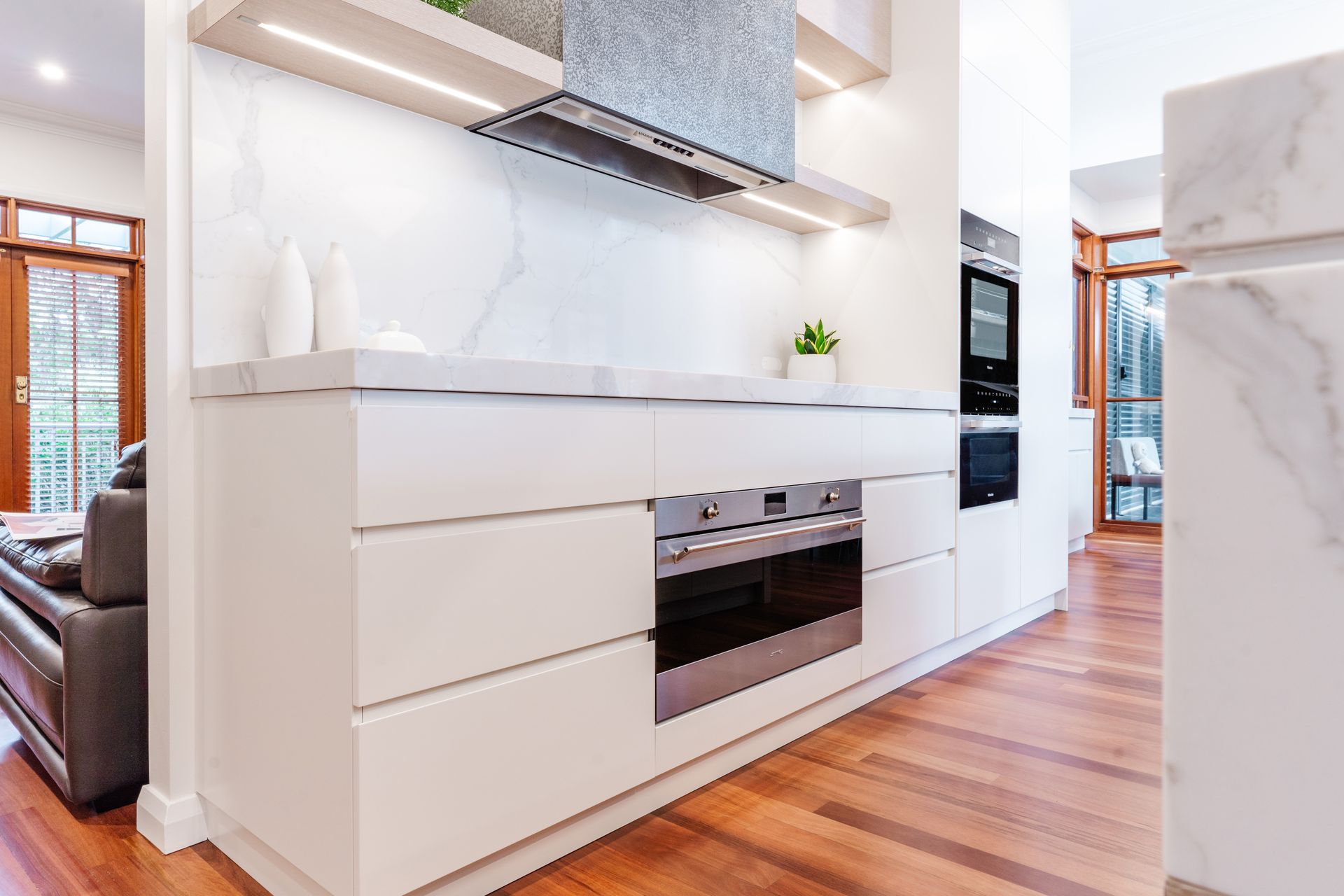 Kitchen With Built-in Oven, Range Hood, and Wooden Floor — PKJ Design in Unanderra, NSW