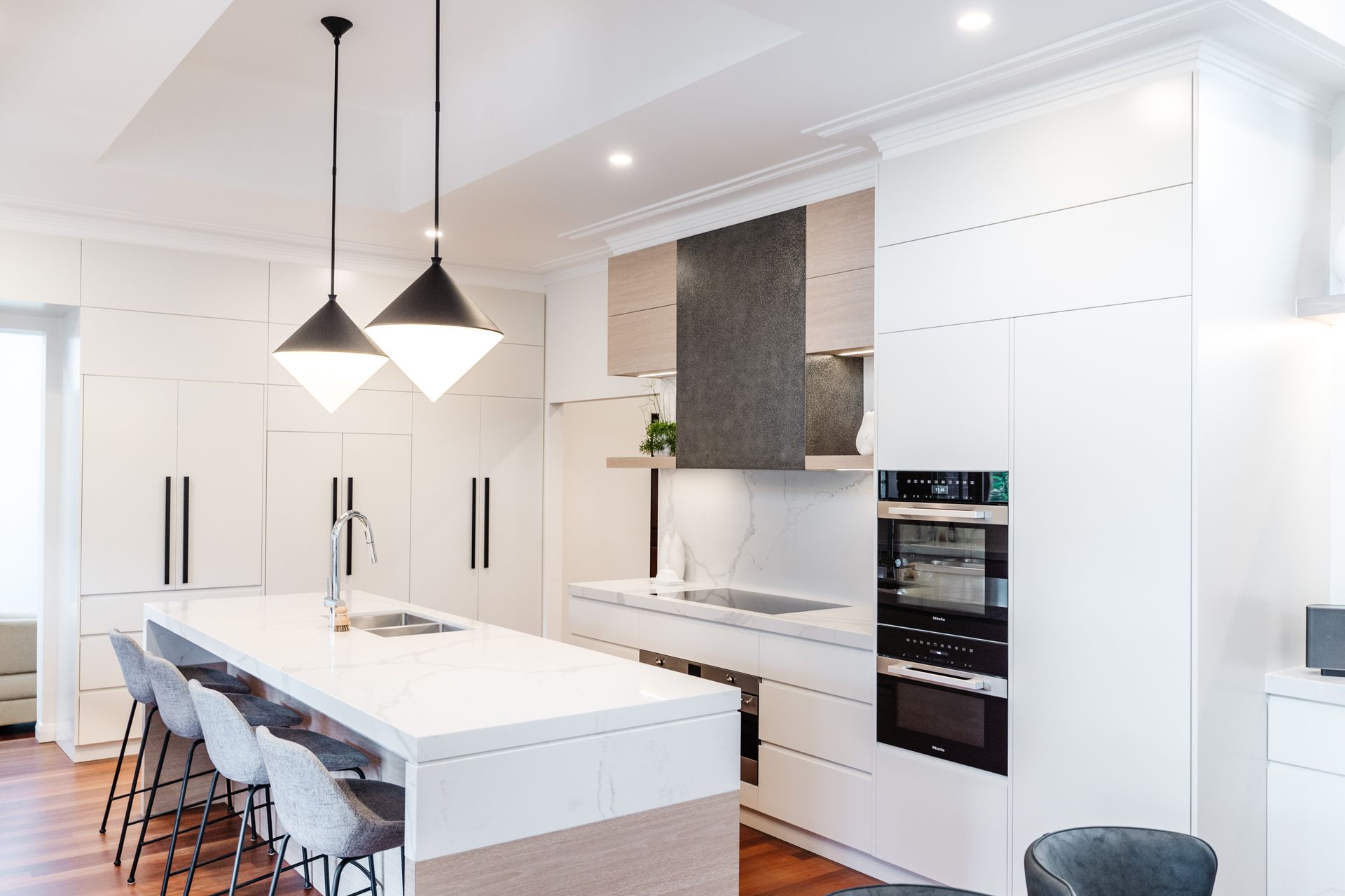 Modern Kitchen With White Cabinets, Island, Pendant Lights, and Ovens — PKJ Design in Unanderra, NSW
